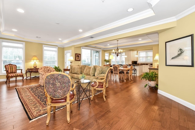 living room with hardwood / wood-style floors, a tray ceiling, crown molding, and a notable chandelier