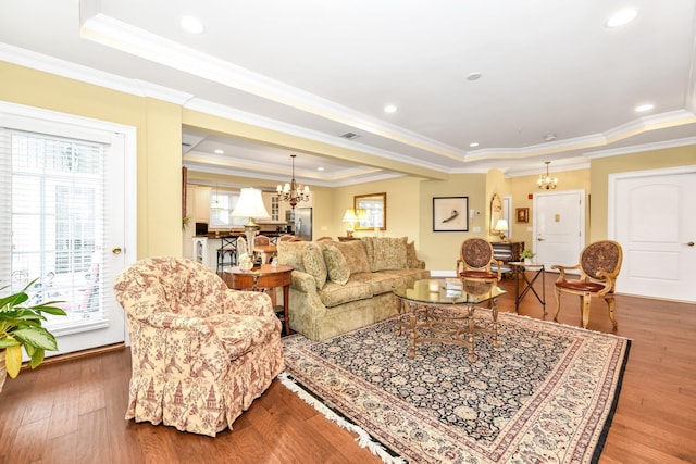 living room featuring a tray ceiling, crown molding, hardwood / wood-style floors, and a chandelier