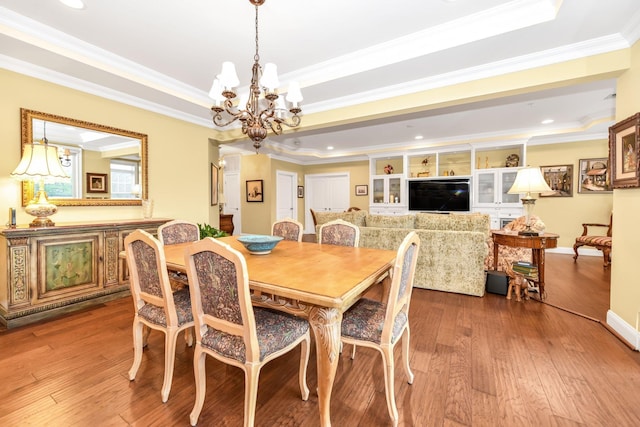 dining room featuring hardwood / wood-style flooring, ornamental molding, a tray ceiling, and an inviting chandelier