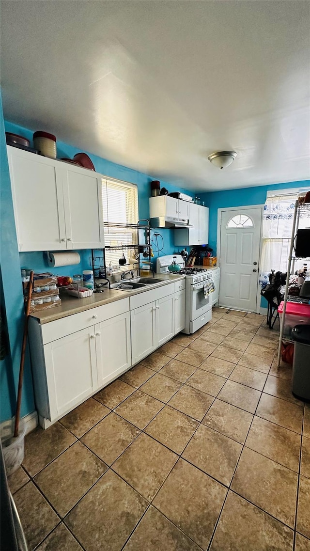 kitchen featuring white gas range, white cabinetry, sink, and light tile patterned flooring