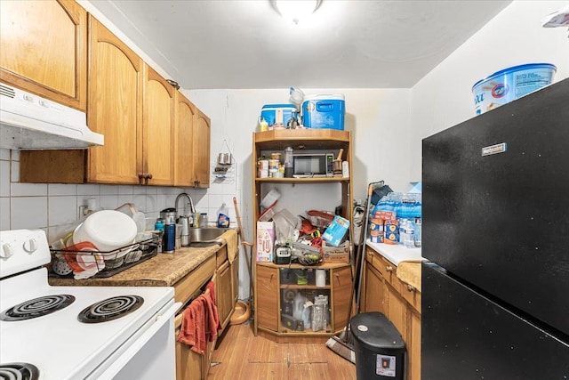 kitchen with black refrigerator, white electric range, sink, light hardwood / wood-style flooring, and decorative backsplash