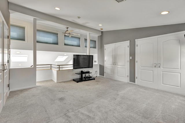 unfurnished living room featuring light carpet, lofted ceiling with skylight, and ceiling fan