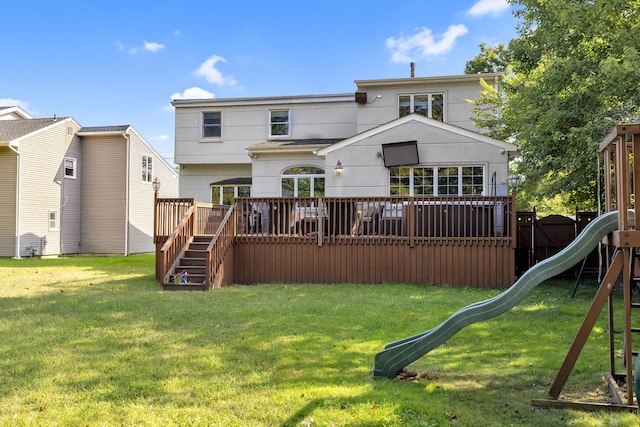 back of house with a lawn, a deck, and a playground