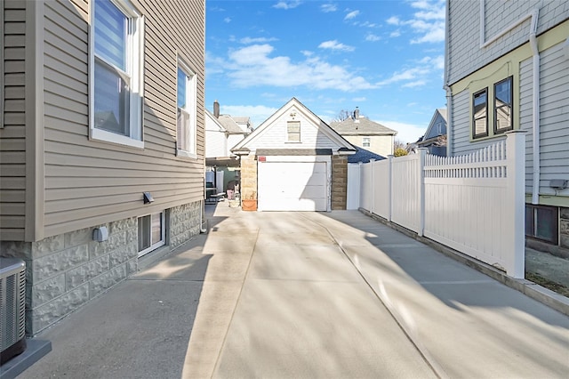 exterior space with an outbuilding, fence, a garage, cooling unit, and driveway