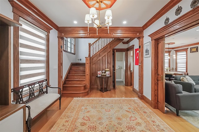 stairway featuring crown molding, wood finished floors, visible vents, baseboards, and an inviting chandelier