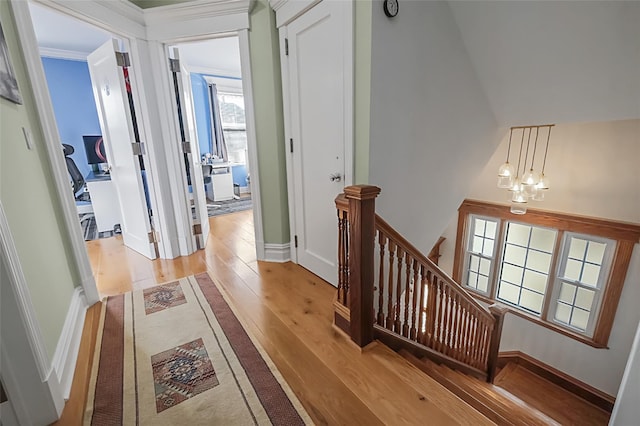 hall with baseboards, a notable chandelier, light wood finished floors, and an upstairs landing