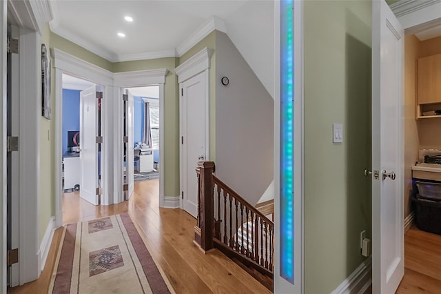 hall featuring crown molding, baseboards, an upstairs landing, and light wood-style floors