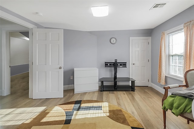 workout area with light wood-style floors, visible vents, and baseboards