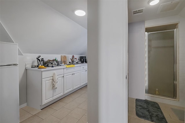 bar with light tile patterned floors, vaulted ceiling, white refrigerator, and visible vents