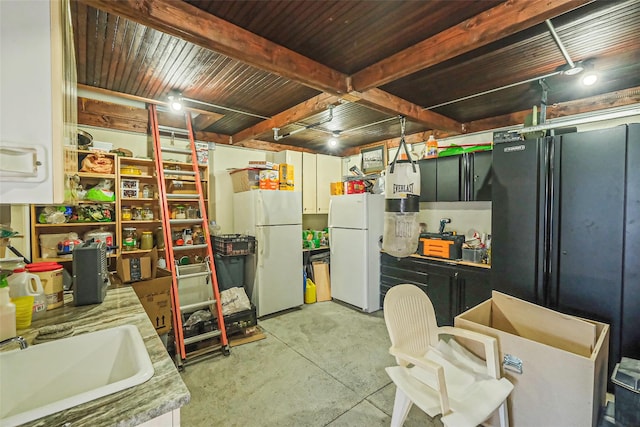 basement featuring freestanding refrigerator and a sink