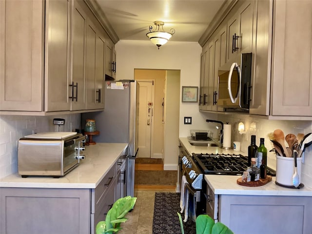 kitchen featuring stainless steel appliances, gray cabinets, tasteful backsplash, and sink