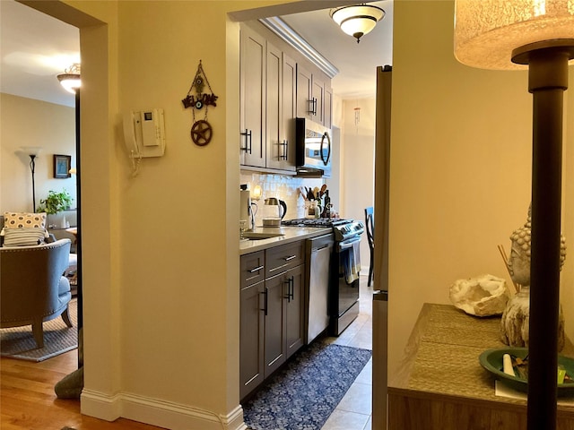 kitchen featuring decorative backsplash, stainless steel appliances, light hardwood / wood-style flooring, and sink