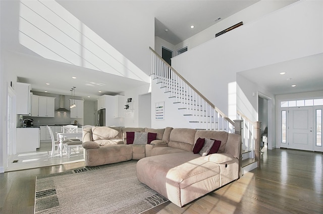 living room featuring a towering ceiling and dark wood-type flooring