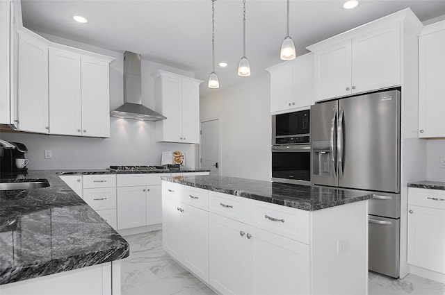 kitchen featuring sink, wall chimney exhaust hood, stainless steel appliances, decorative light fixtures, and a kitchen island