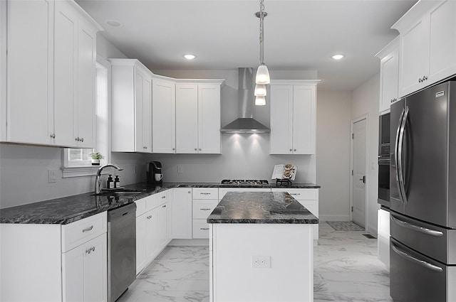 kitchen featuring white cabinetry, a center island, stainless steel appliances, wall chimney range hood, and pendant lighting