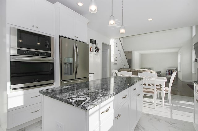 kitchen featuring a center island, dark stone counters, white cabinets, decorative light fixtures, and stainless steel appliances