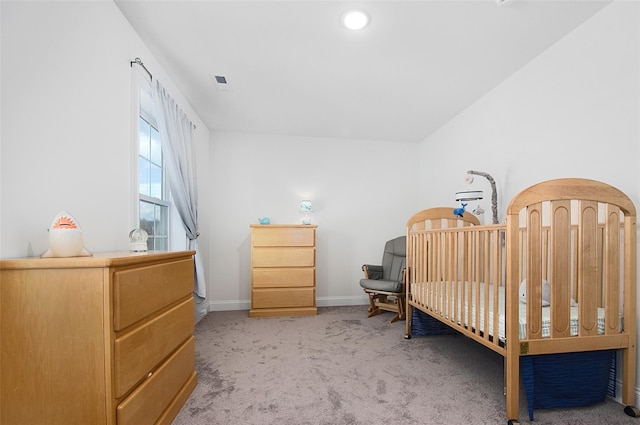 bedroom with light colored carpet and a nursery area