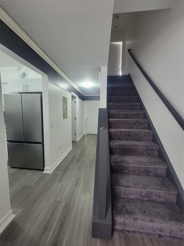 stairs with electric panel, hardwood / wood-style flooring, and ornamental molding
