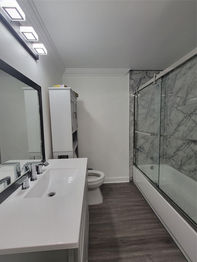 full bathroom with bath / shower combo with glass door, vanity, crown molding, wood-type flooring, and toilet
