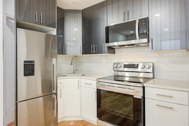 kitchen with appliances with stainless steel finishes, tasteful backsplash, dark brown cabinets, sink, and white cabinets