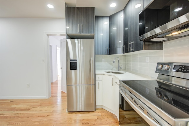 kitchen featuring backsplash, sink, light hardwood / wood-style flooring, appliances with stainless steel finishes, and white cabinetry