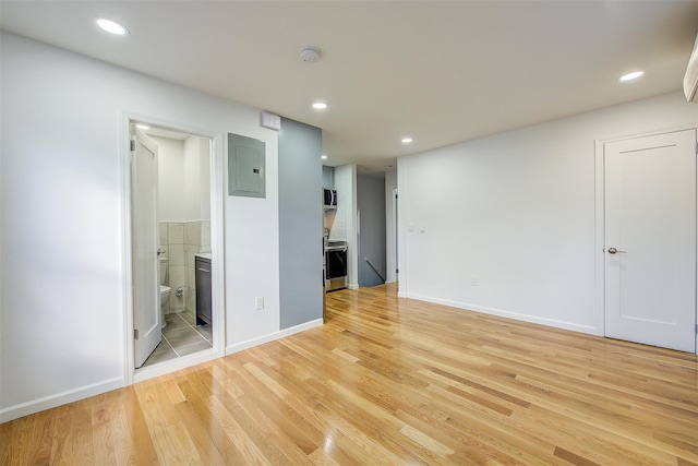 spare room with electric panel and light hardwood / wood-style floors