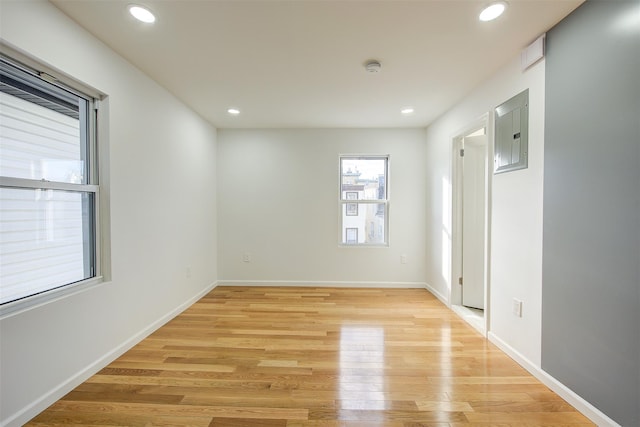 empty room with light hardwood / wood-style floors and electric panel