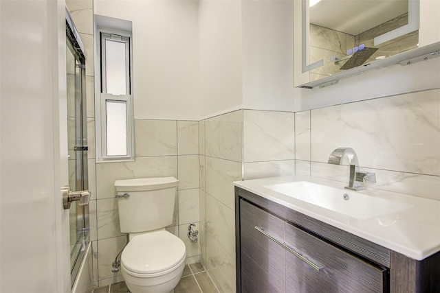 bathroom with a wealth of natural light, vanity, toilet, and tile walls