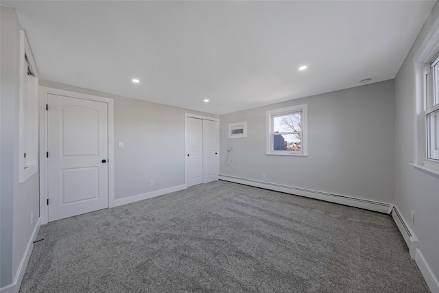 spare room with carpet floors and a baseboard heating unit