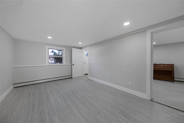 basement with baseboard heating and light hardwood / wood-style flooring