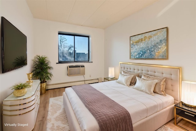 bedroom with baseboard heating, a wall unit AC, and light hardwood / wood-style flooring