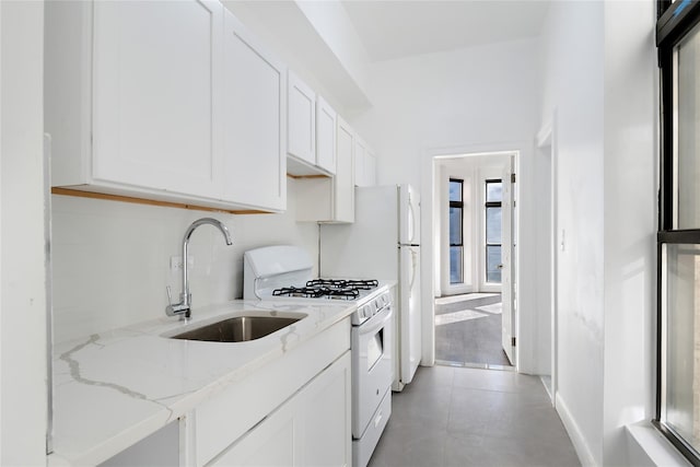 kitchen with white cabinetry, light stone counters, sink, and white range with gas stovetop