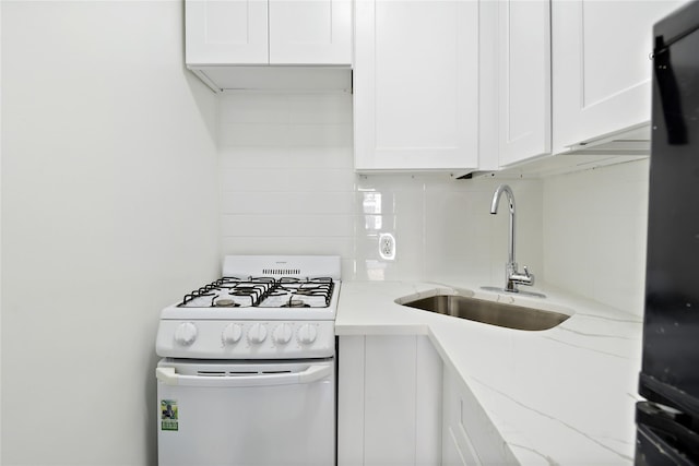 kitchen featuring light stone countertops, white cabinetry, gas range gas stove, and sink