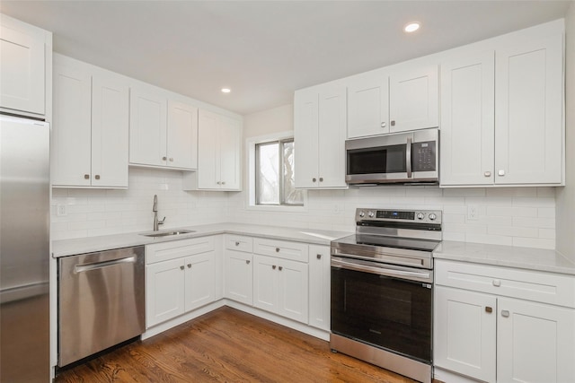 kitchen featuring dark hardwood / wood-style flooring, tasteful backsplash, stainless steel appliances, sink, and white cabinets