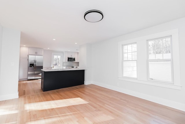 kitchen featuring kitchen peninsula, white cabinetry, stainless steel appliances, and light hardwood / wood-style floors