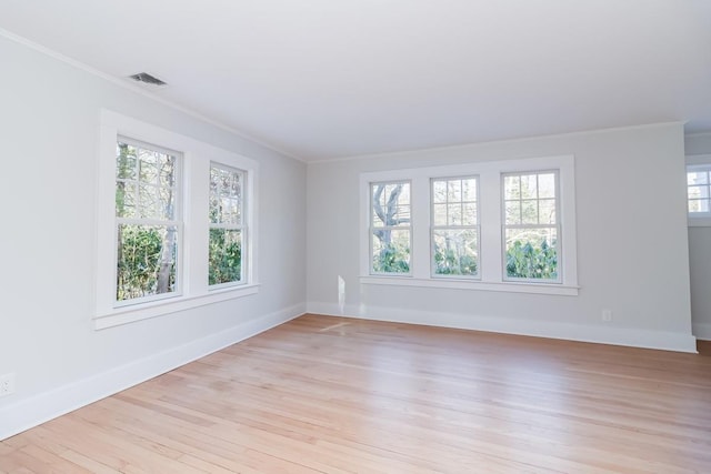 spare room featuring a wealth of natural light, crown molding, and light wood-type flooring