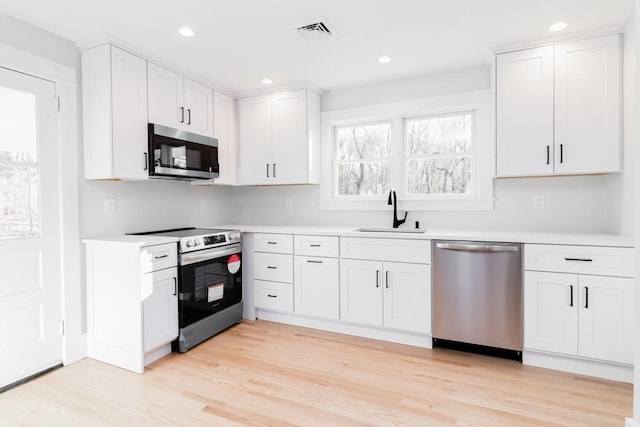 kitchen with white cabinets, sink, light wood-type flooring, and stainless steel appliances