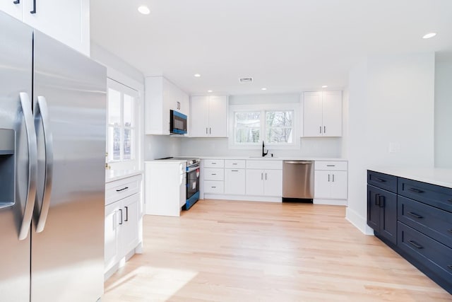 kitchen featuring white cabinets, sink, appliances with stainless steel finishes, and light hardwood / wood-style flooring