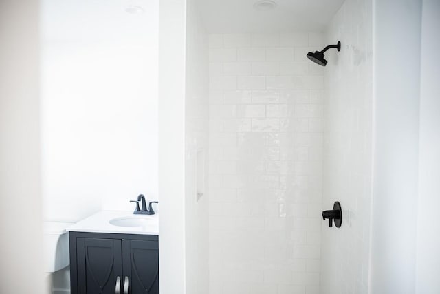 bathroom with a tile shower, vanity, and toilet