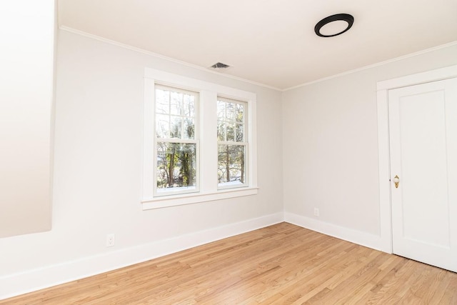 spare room with light wood-type flooring and crown molding