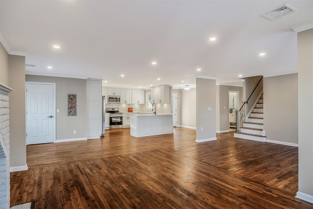 unfurnished living room featuring dark hardwood / wood-style flooring, crown molding, and sink