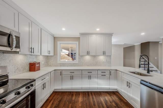 kitchen with white cabinetry, sink, stainless steel appliances, dark hardwood / wood-style floors, and kitchen peninsula