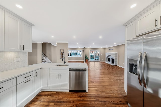 kitchen with white cabinets, sink, a fireplace, dark hardwood / wood-style flooring, and stainless steel appliances