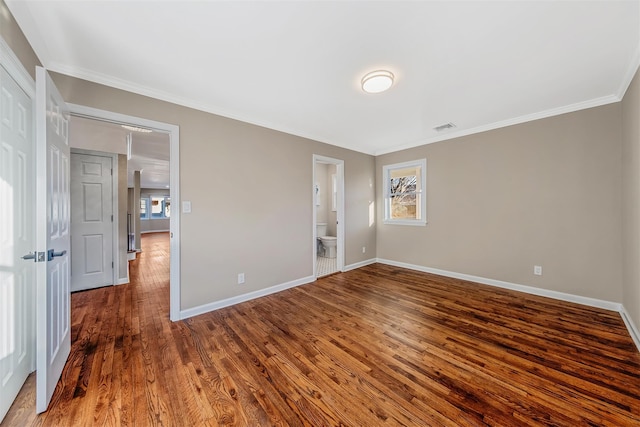 unfurnished bedroom featuring ensuite bathroom, crown molding, and dark hardwood / wood-style floors