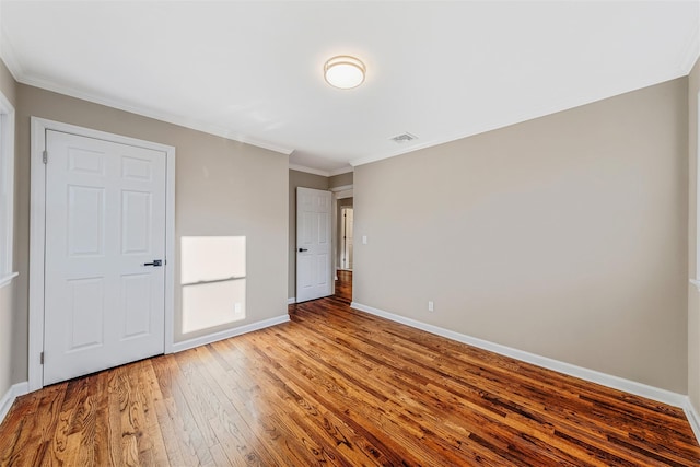 unfurnished bedroom with hardwood / wood-style flooring and crown molding