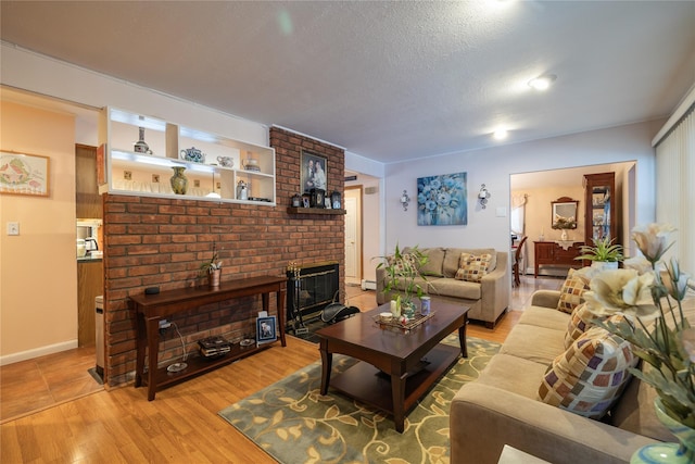 living room featuring a baseboard radiator, light hardwood / wood-style floors, a textured ceiling, and a brick fireplace