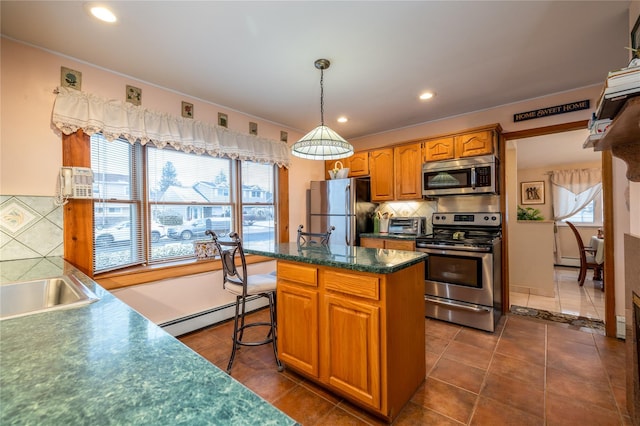 kitchen with stainless steel appliances, dark tile patterned floors, a baseboard heating unit, pendant lighting, and a center island