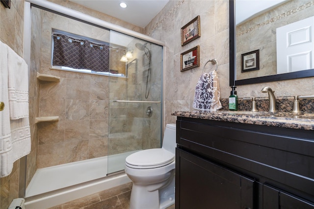 bathroom with vanity, toilet, walk in shower, and tile walls