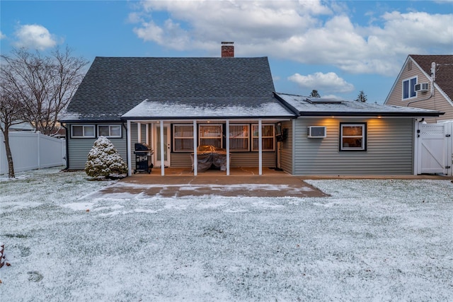 snow covered house with a patio and a wall unit AC