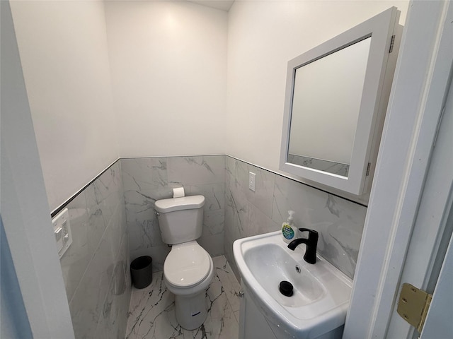 bathroom with sink, tile walls, and toilet